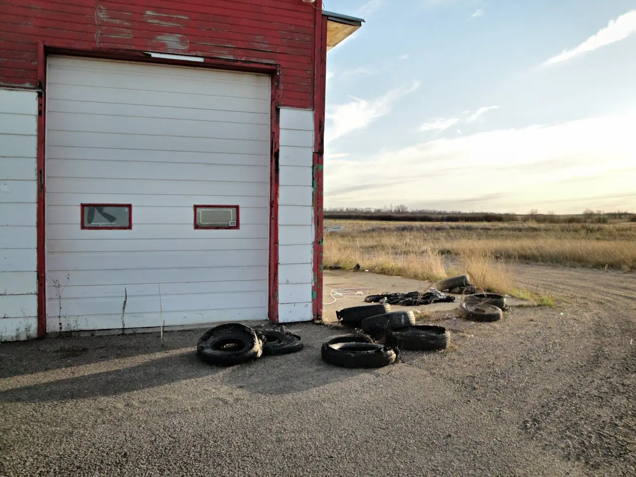 Old red garage with discarded tires beside the prairie, 2011